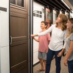 A female customer and her two children shop wood garage doors in the Overhead Inc. showroom