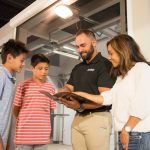 A female customer and her two sons talk about garage door features with a garage door installer